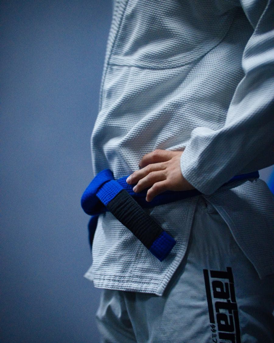 Main serrant une ceinture bleue sur un kimono blanc