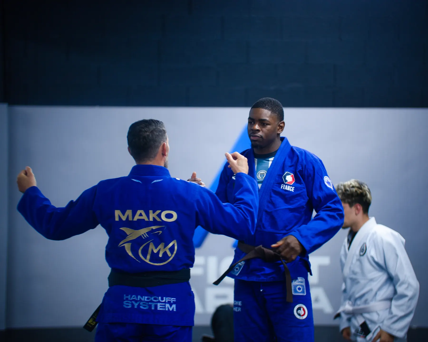 Un coach en kimono floqué explique un mouvement à un élève