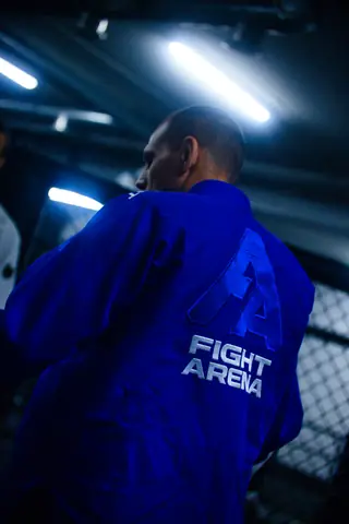 Pratiquant de dos, kimono bleu floqué Fight Arena, sous les néons du dojo