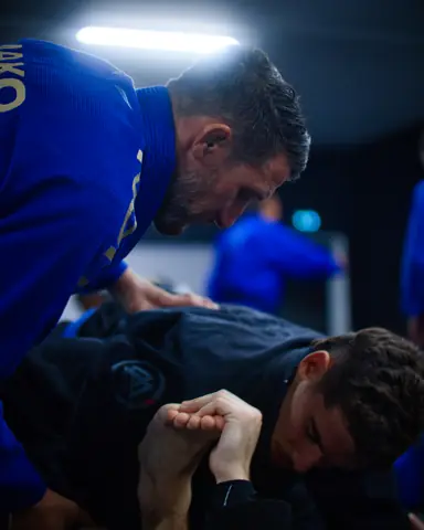 Un coach penché sur un élève pour corriger une prise