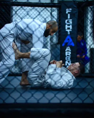Échange de JJB en kimono blanc photographié à travers le grillage de la cage