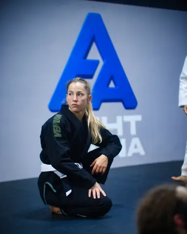 Pratiquante assise sur le tapis devant le logo Fight Arena