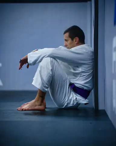Pratiquant ceinture violette assis contre le mur, en récupération